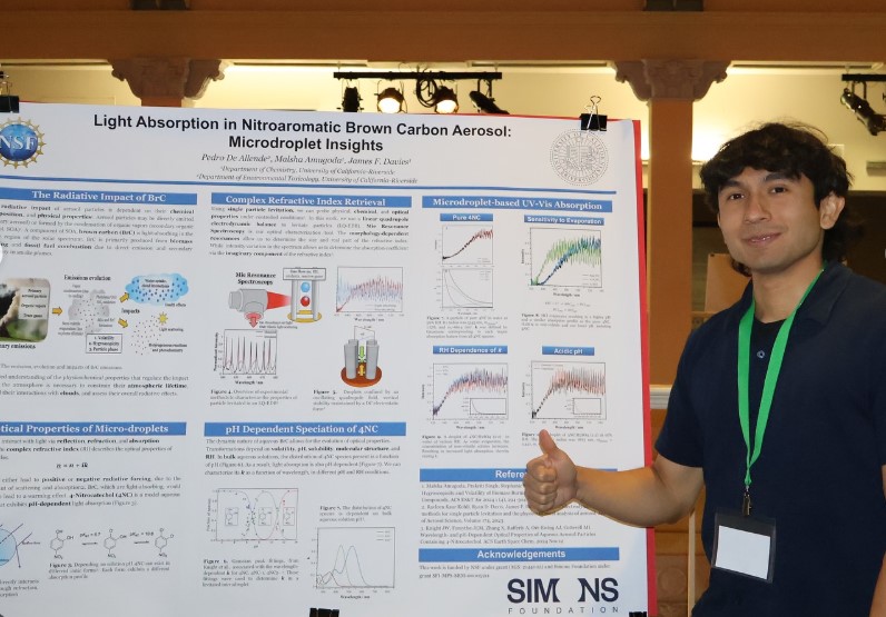 Pedro De Allende giving a thumbs up in front of his research poster