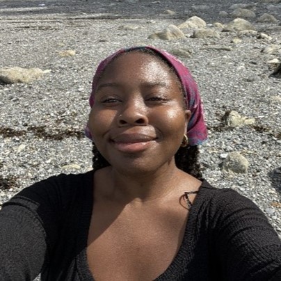 Headshot of Tamar Crump smiling in a black long sleeved shirt and a maroon bandana