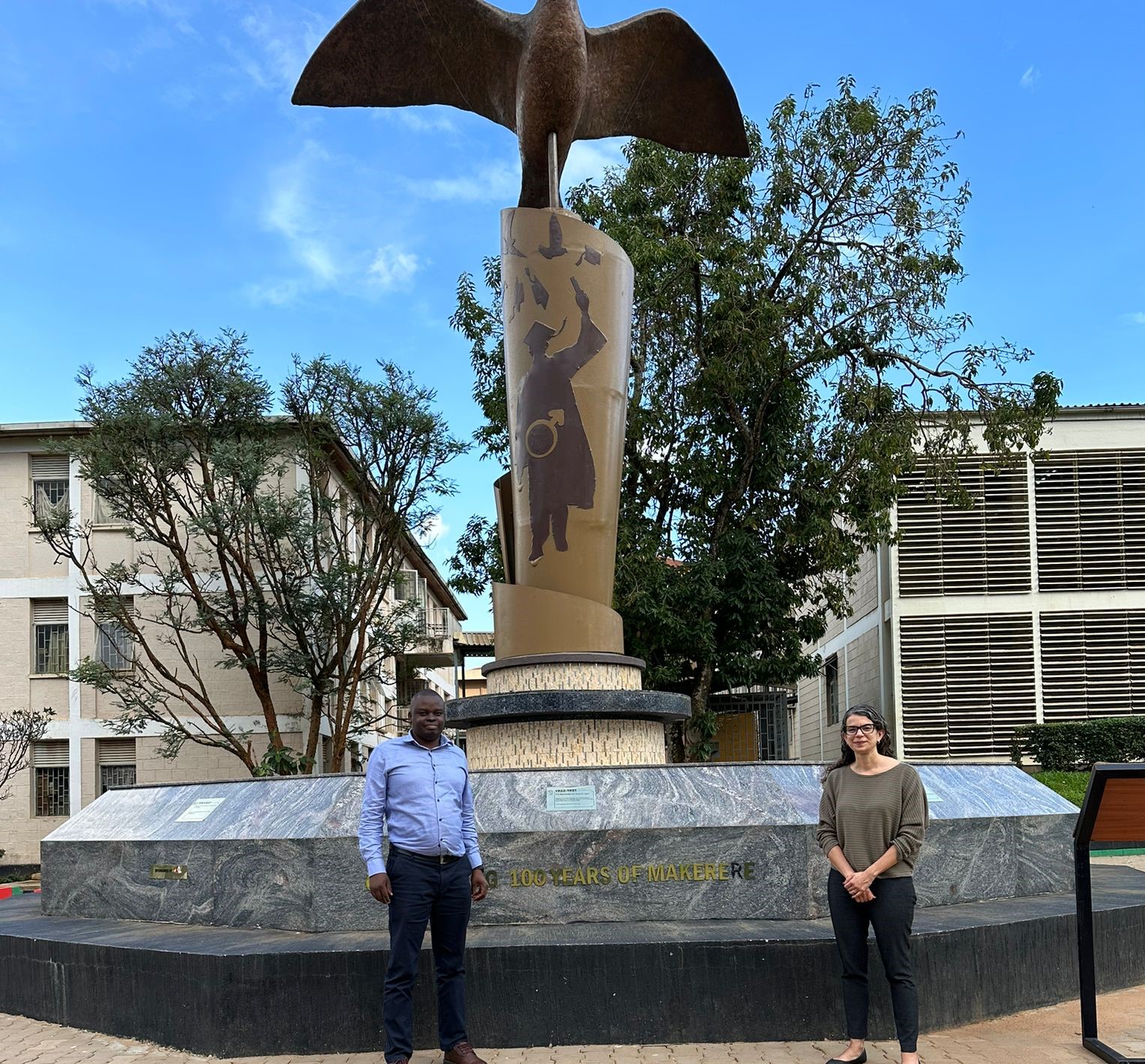 Stephen and Monica standing in front of a statue at Makerere University