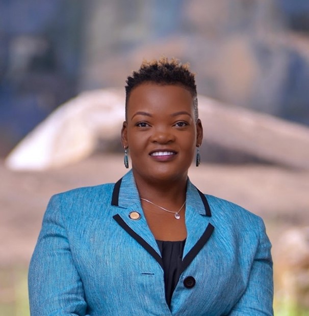 Headshot of Scholar Matovu wearing a blue blazer and matching earrings.