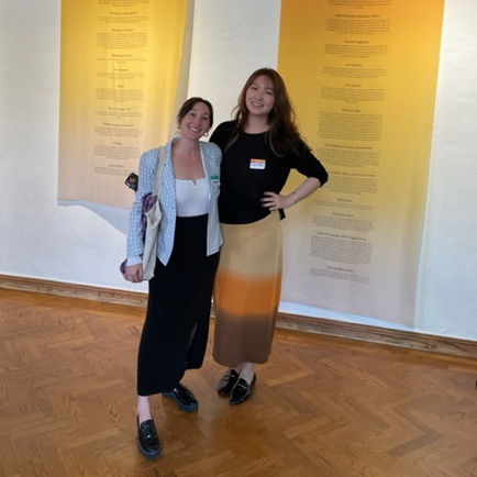 Two women posing in front of exhibit wall