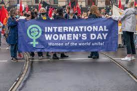 women marching and holding a banner for International Women's Day